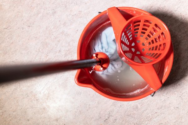 top view of mop rinsing in red bucket with water
